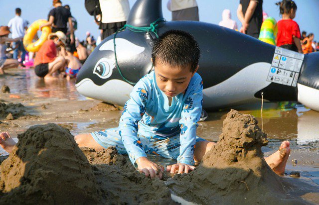 Một em nhỏ nghịch cát trên bãi biển